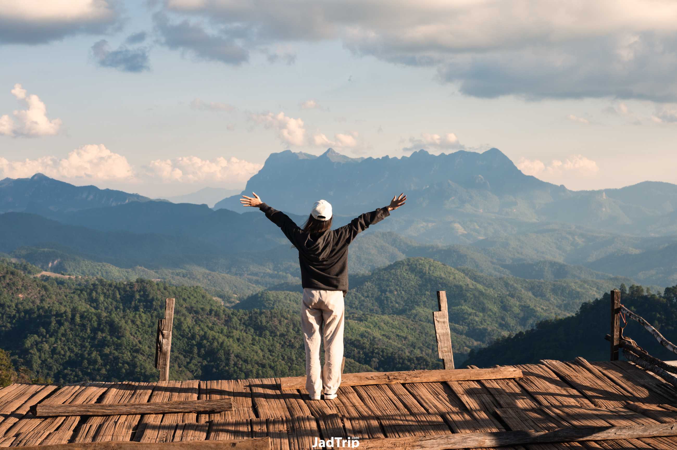 cheerful-back-view-asian-woman-standing-arms-raised-wooden-balcony-with-mountain.jpg